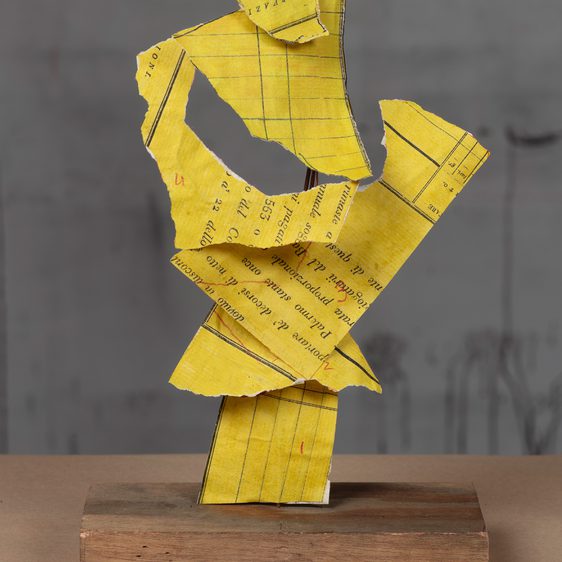 A yellow abstract sculpture which is painted to look like ripped up lined note paper.