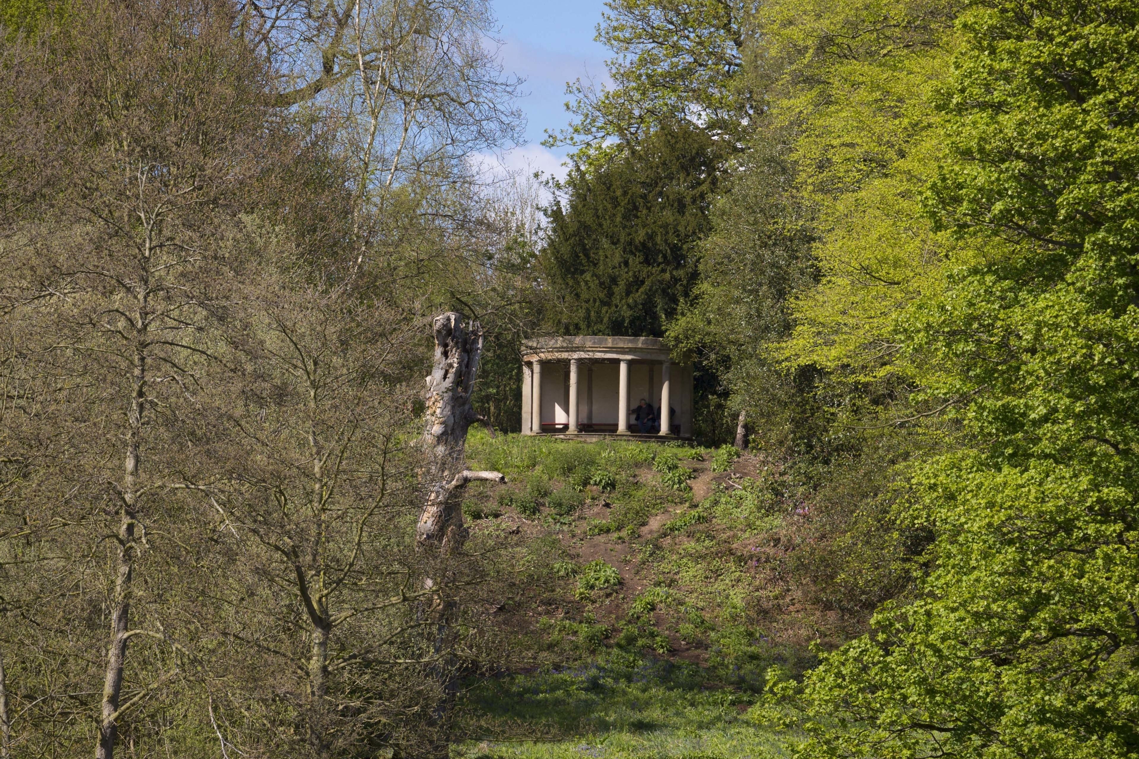 Building resembling a Greek temple on a hill above the lake, surrounded by trees.