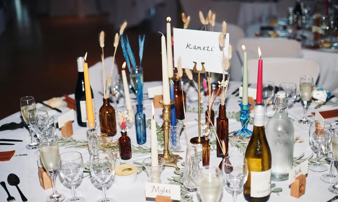 A table, set with glasses candles and wedding favours.