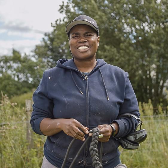 A black woman wearing a blue hoody, standing in a field at YSP