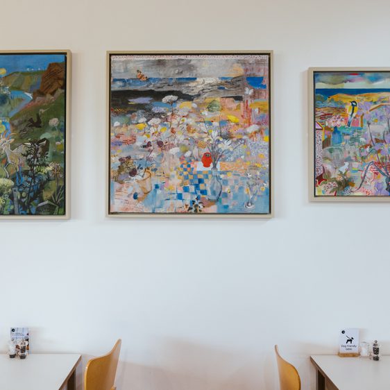 Three framed abstract paintings depicting birds and foliage, displayed on a white gallery wall.