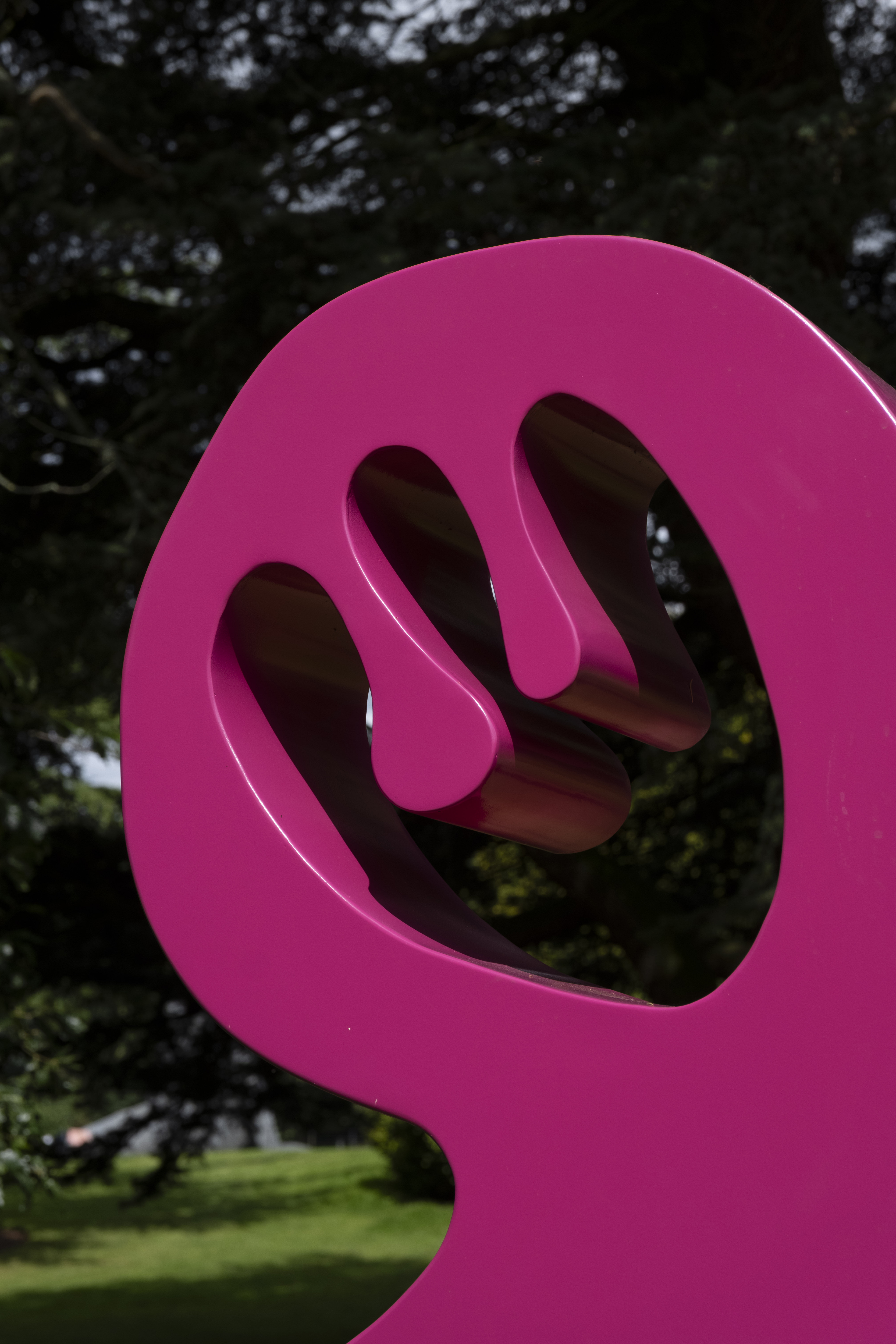 A close up of a bright pink abstract sculpture outdoors