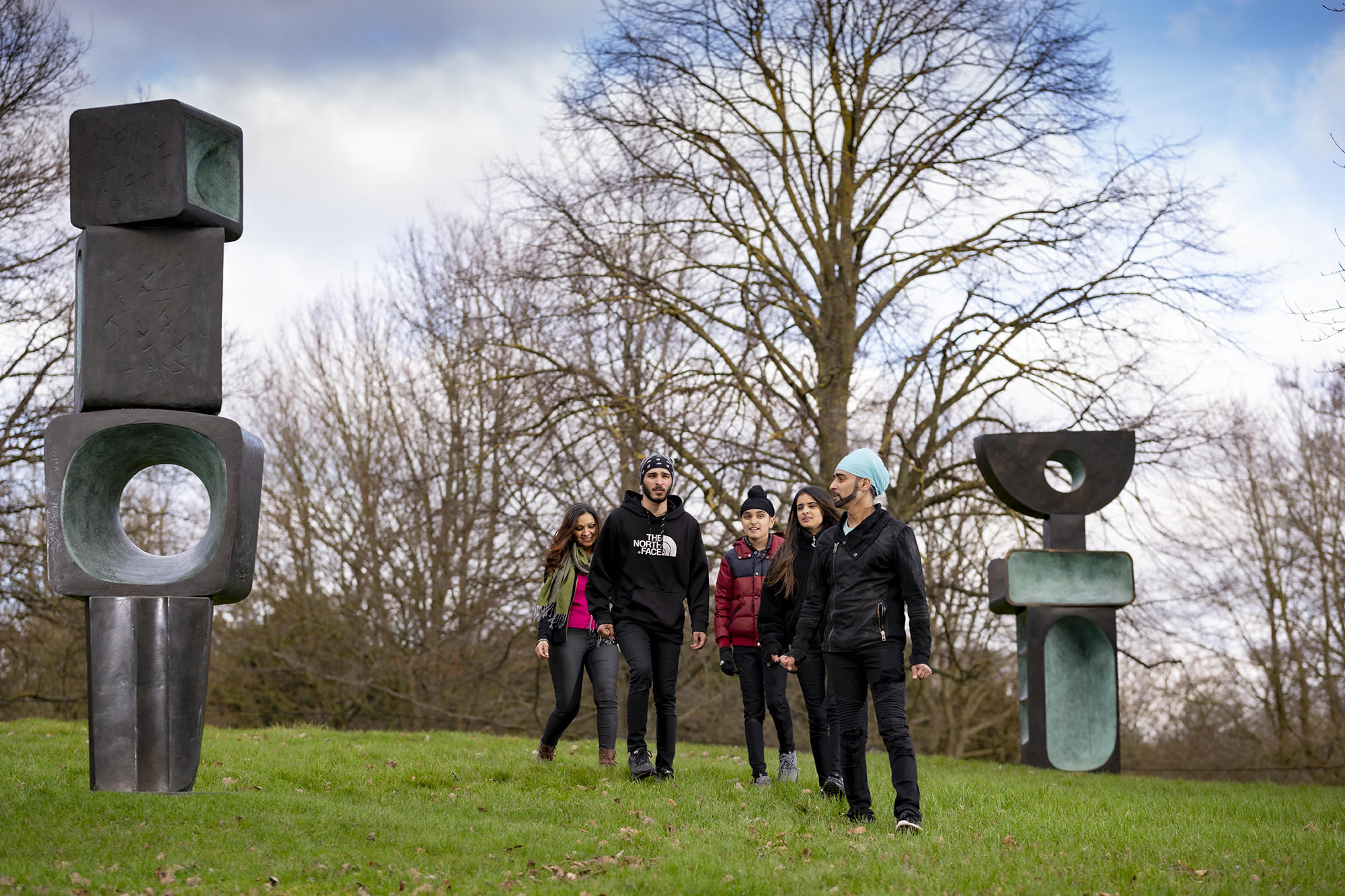 A group of people standing in front of Barbara Hepworth, The Family of Man at Yorkshire Sculpture Park