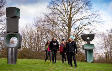 A group of people standing in front of Barbara Hepworth, The Family of Man at Yorkshire Sculpture Park