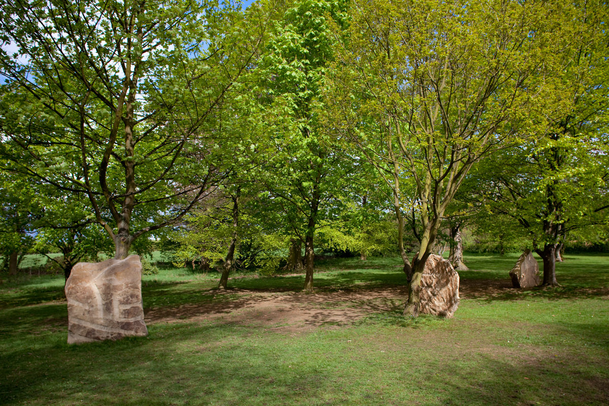 Three large stones, with trees growing behind them