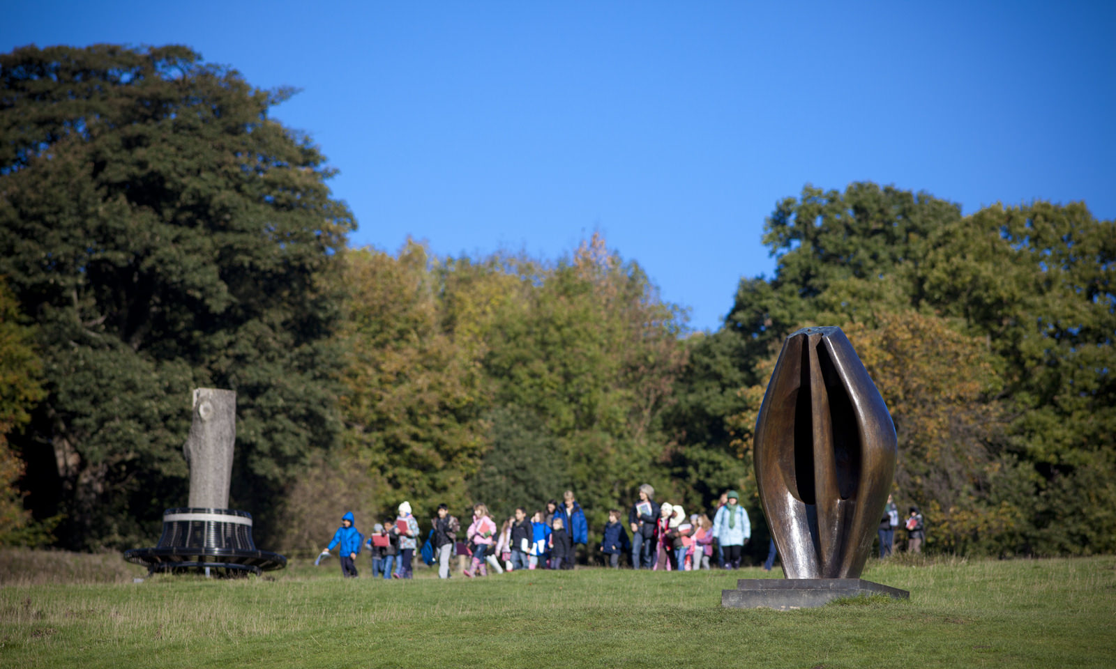 Group of people standing behind Henry Moore Large Totem Head at Yorkshire Sculpture Park