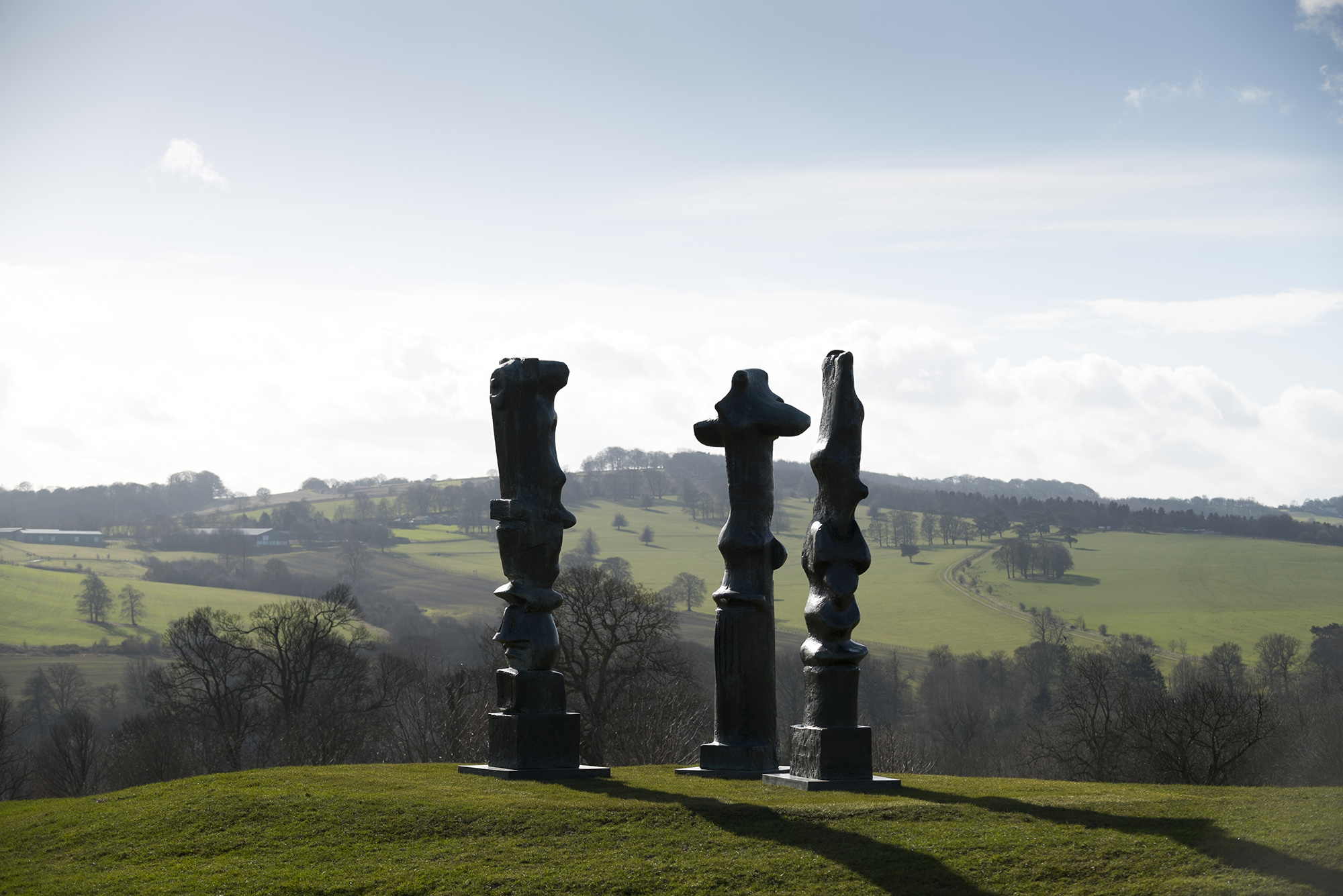 Three tall thin bronze sculptures looking out over the landscape