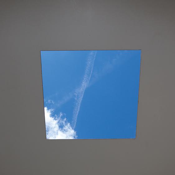 The view through a square hole in the roof of Skyspace, showing a blue sky with clouds and airplane trails