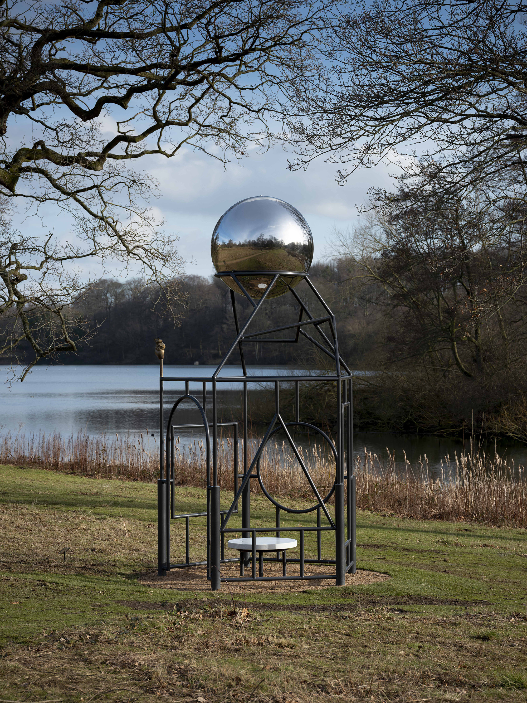 A metal frame sculpture with a silver ball at the top.