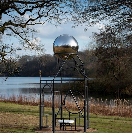 A metal frame sculpture with a silver ball at the top.