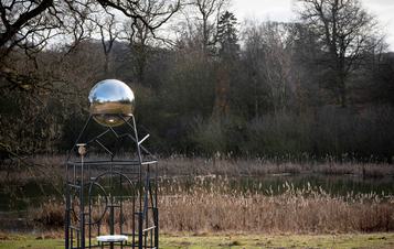 A metal frame sculpture with a silver ball at the top.