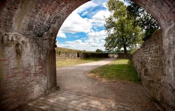The view from a brick archway out over the countryside with a blue, cloudy sky
