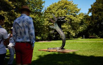 people looking at a 3 headed snake sculpture outdoors