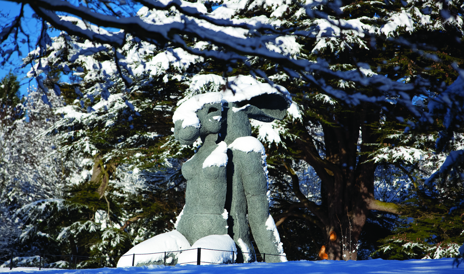 A sculpture with a woman's body and a rabbit head, covered in snow
