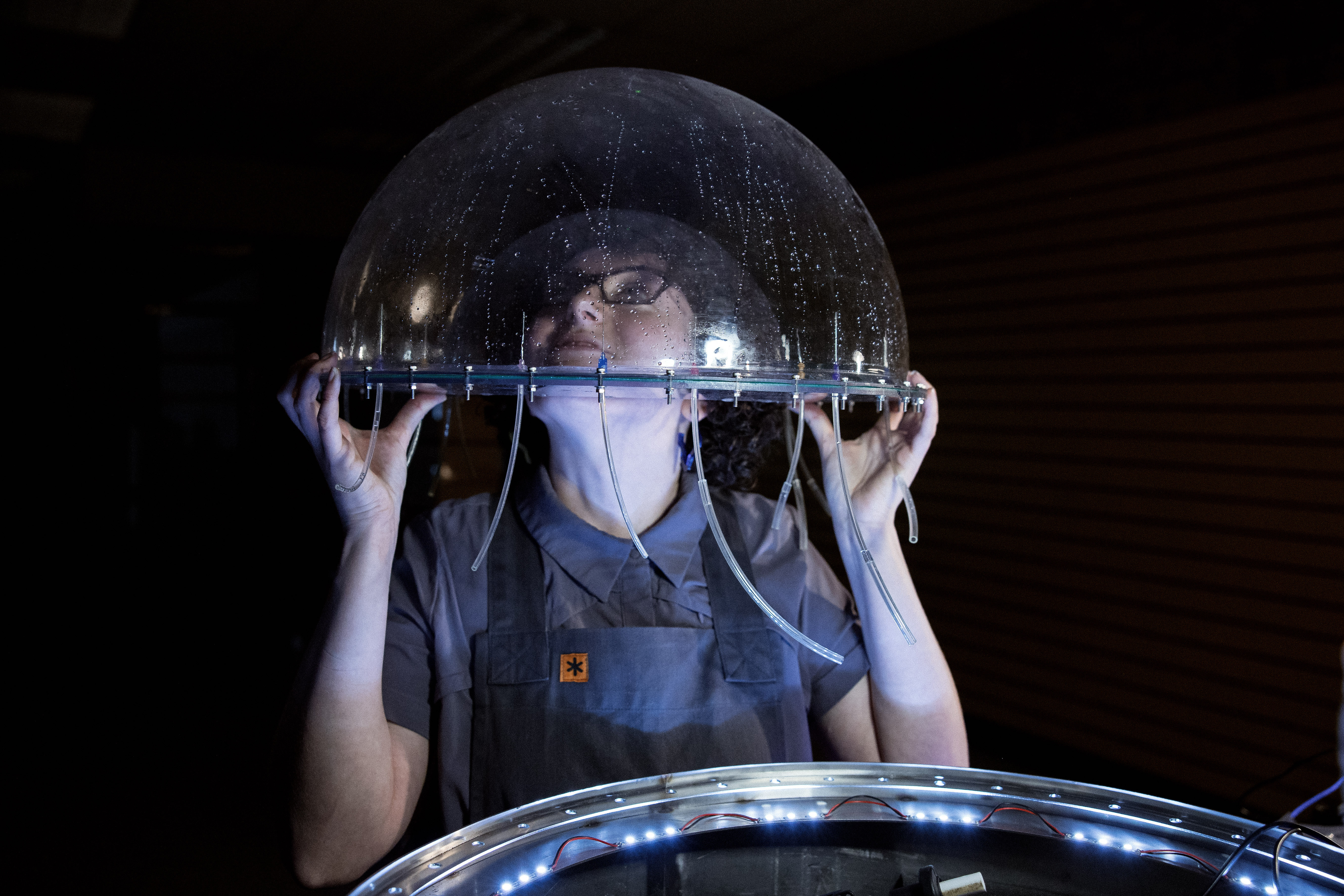 a person with their head inside a clear bubble-like plastic dome