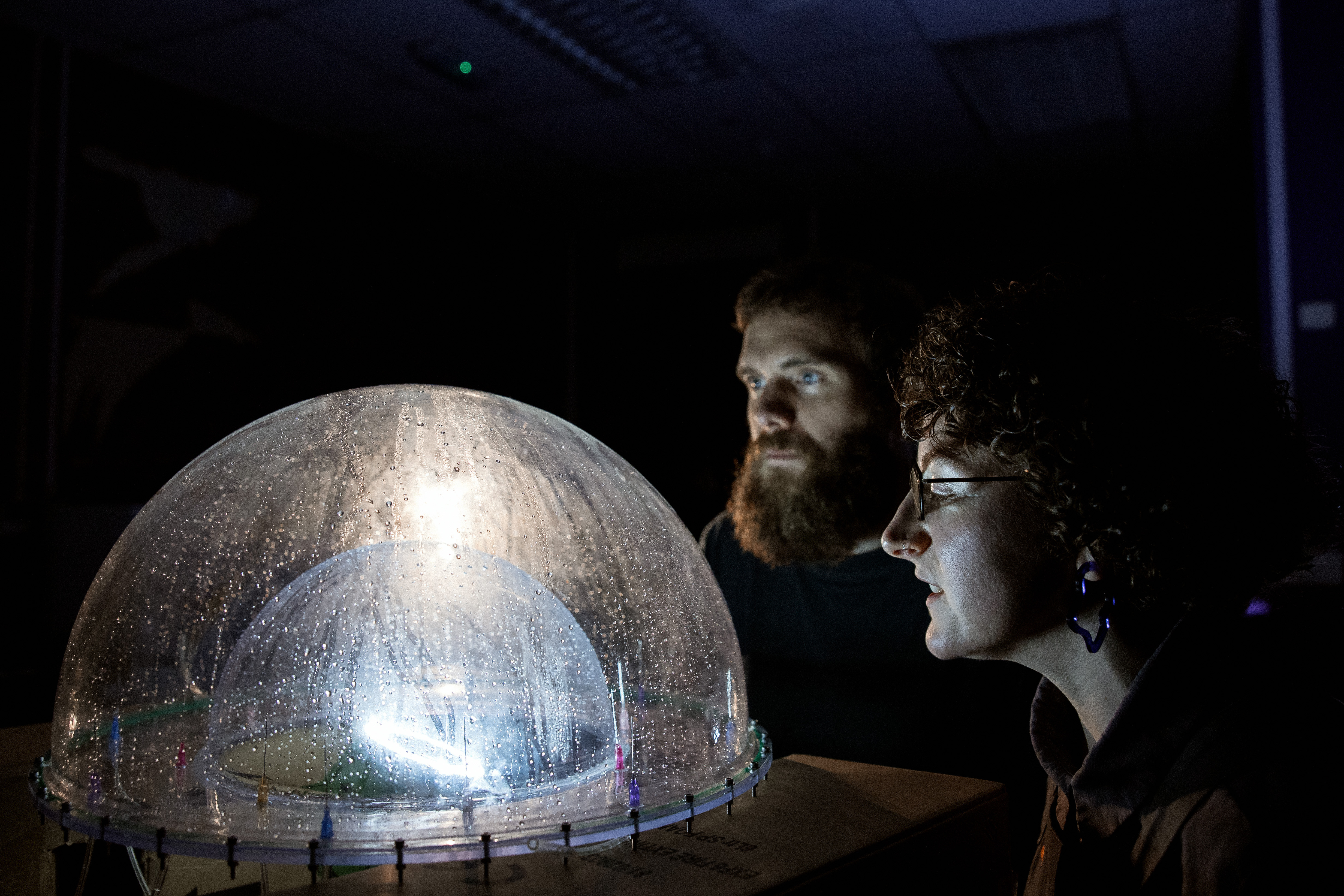 Two people looking into an illuminated plastic dome