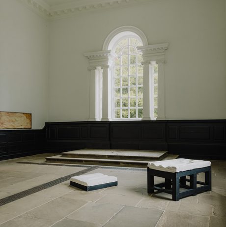 A gallery installation of framed wall based works, plaster works on black plinths and a hanging paper work suspended from the ceiling.