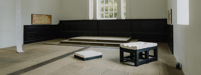 A gallery installation of framed wall based works, plaster works on black plinths and a hanging paper work suspended from the ceiling.