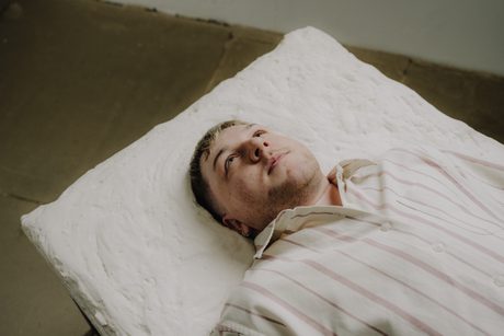 A person holds a large, intricate wasp nest made of grey paper-like material.
