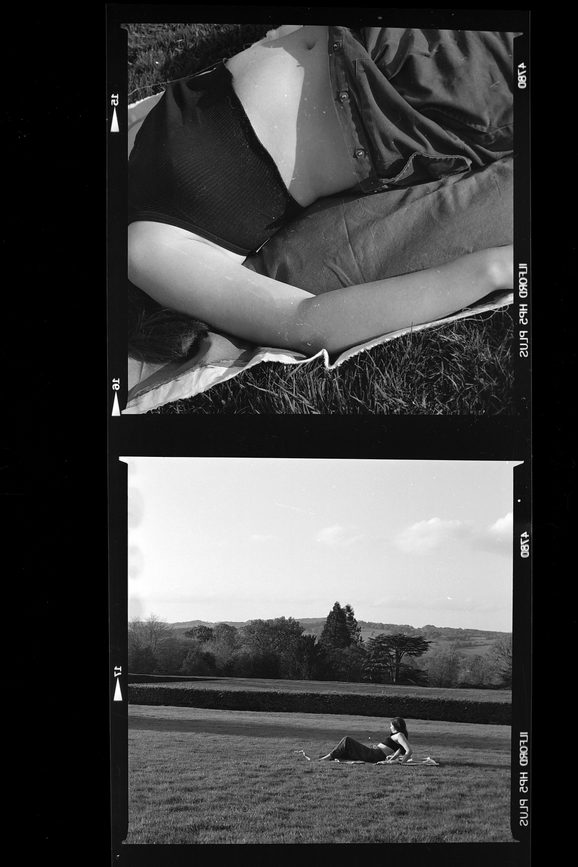 Black and white negative prints of a person lying down in a natural environment.