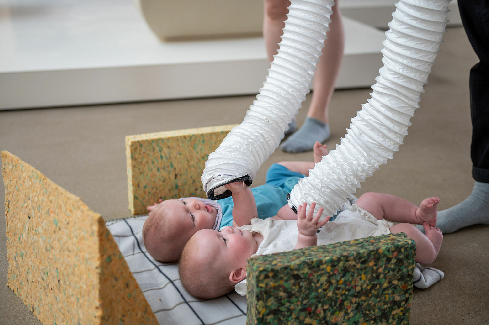 Two babies playing with long white tubes