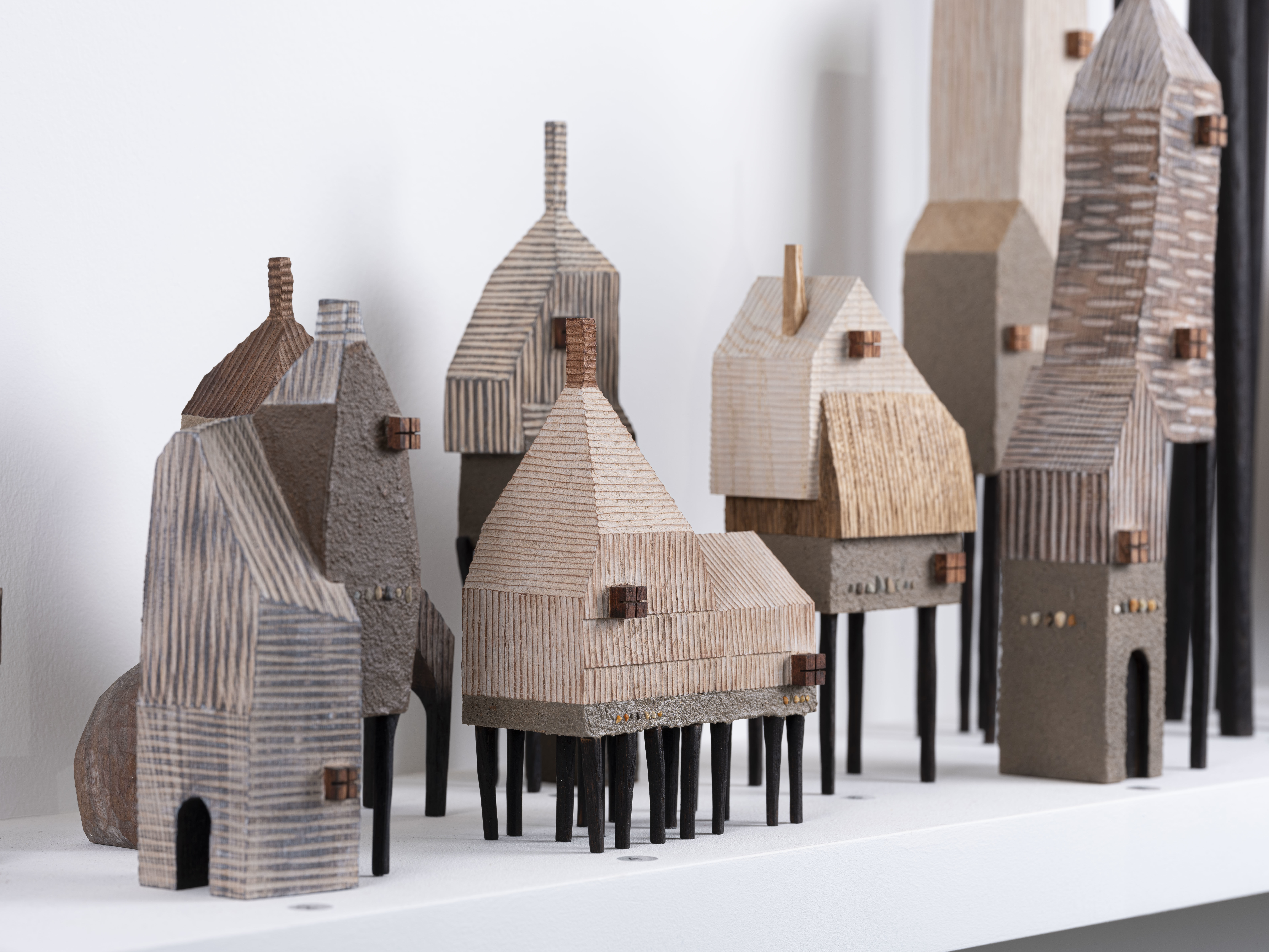 Multiple miniature handcrafted houses on a shelf.