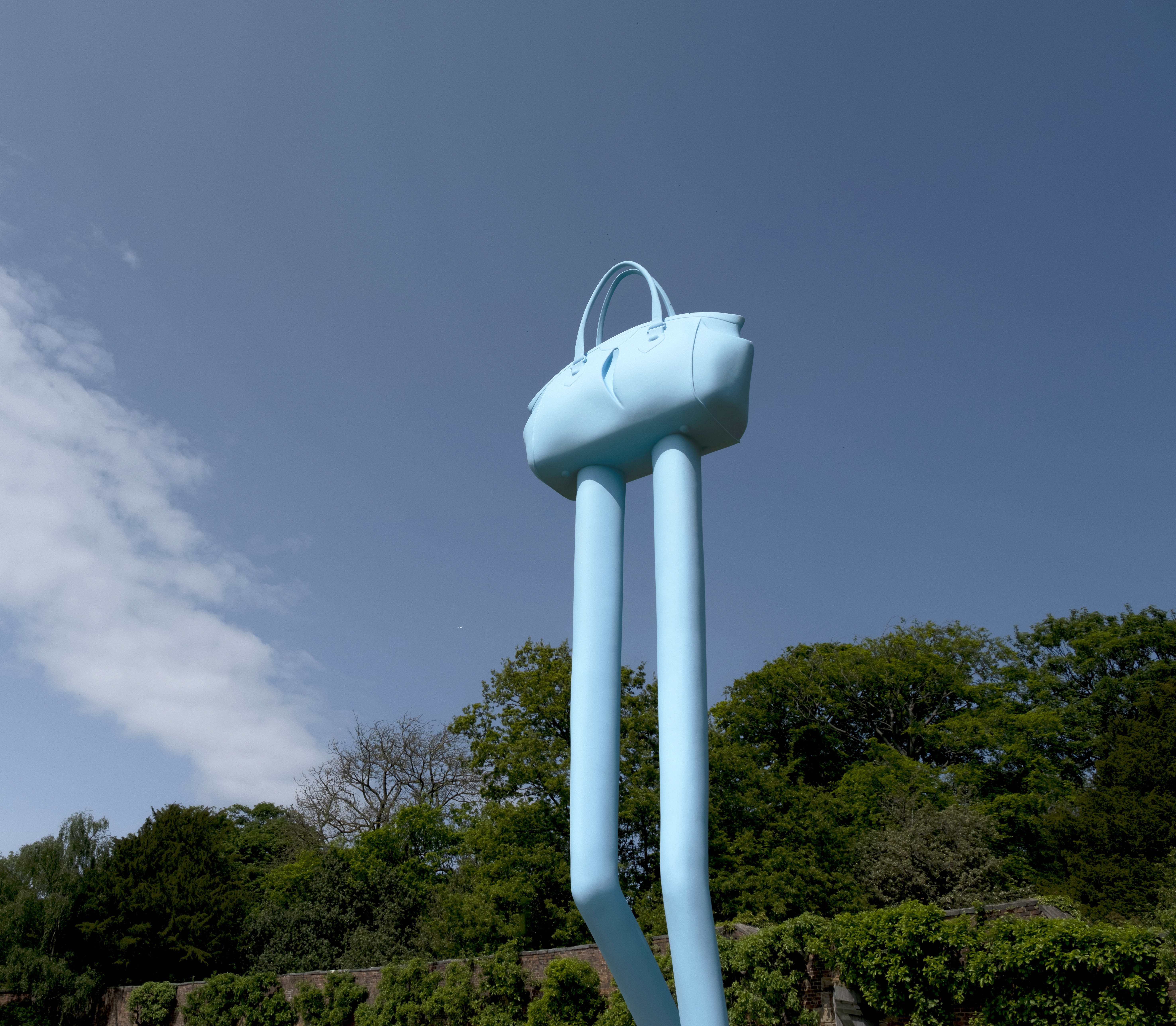 A blue handbag sculpture with long thin legs
