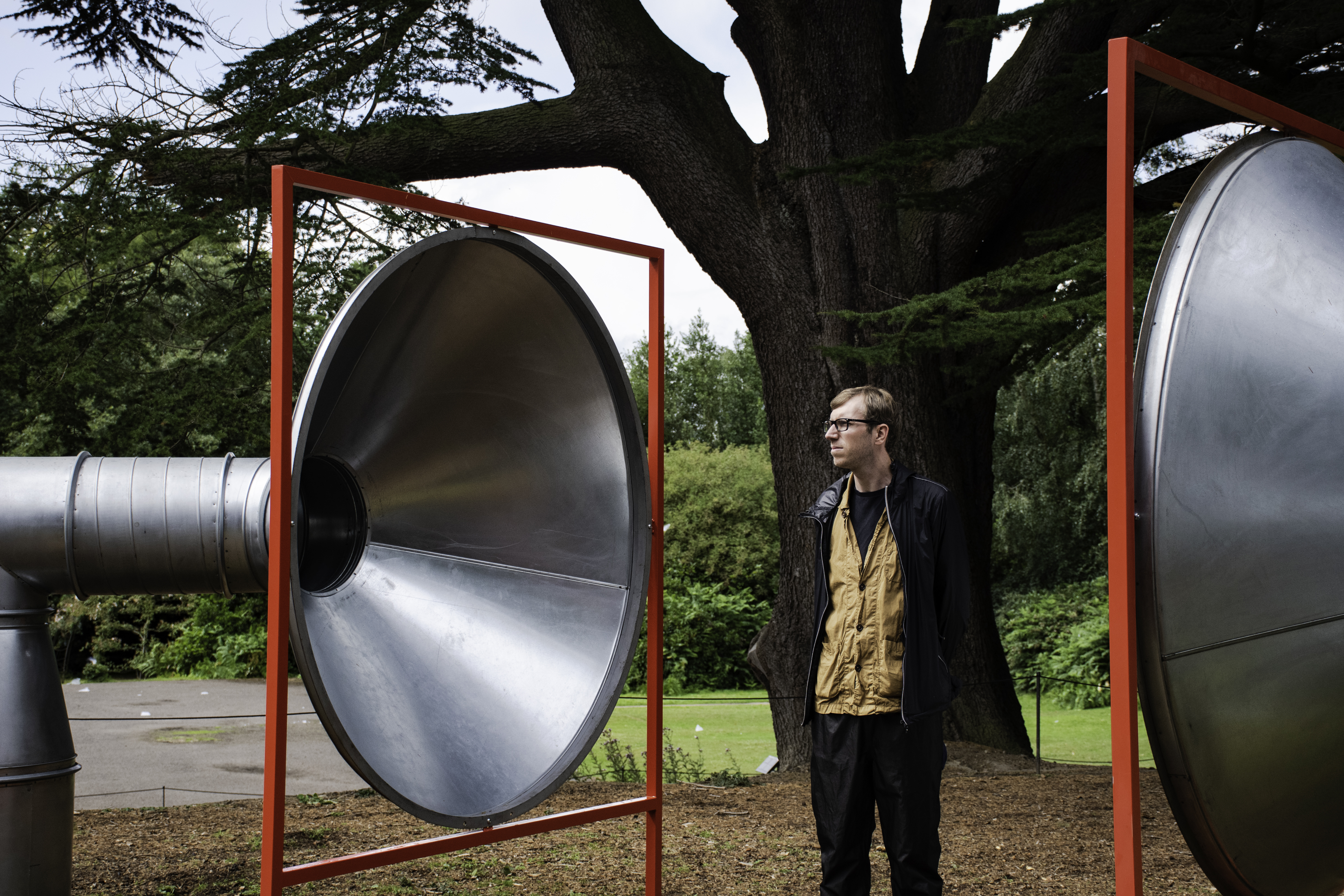 A man standing in between two giant silver tubes with red frames