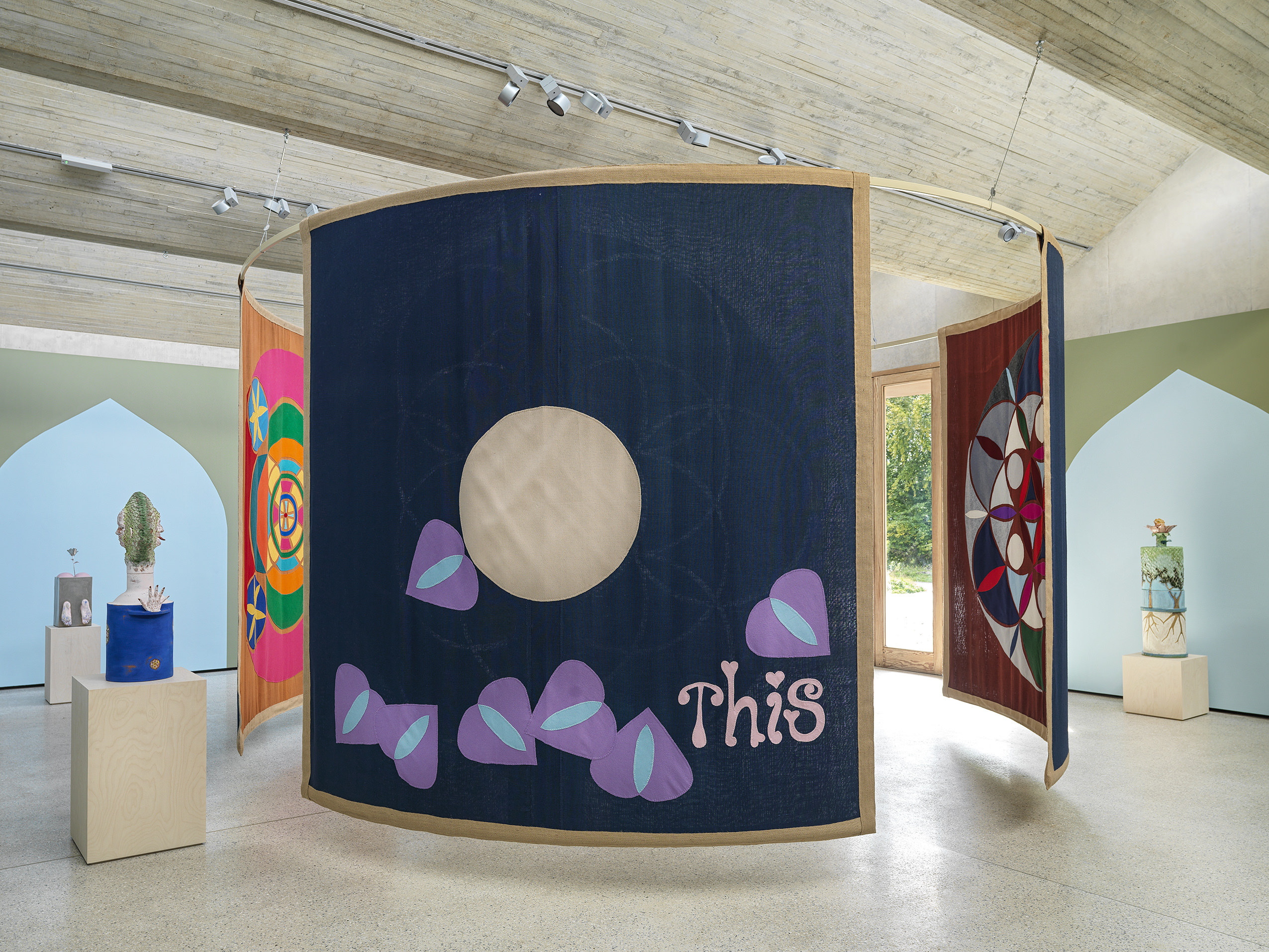 A series of fabric hangings in the centre of a gallery space.