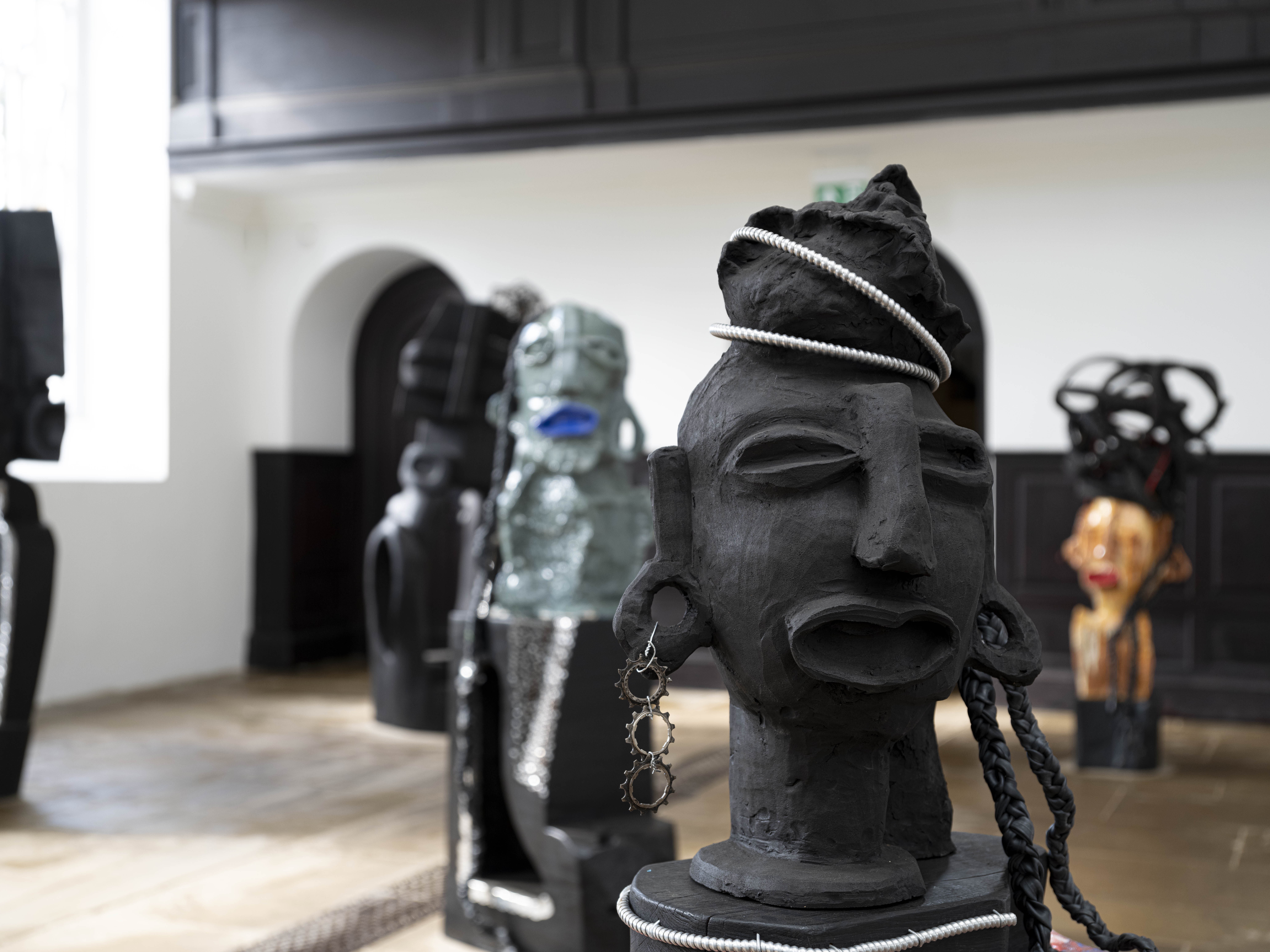A collection of carved wood and ceramic figures in a gallery.
