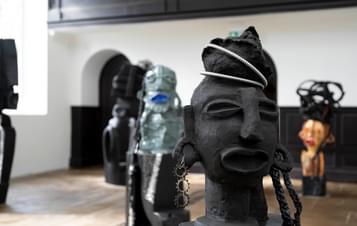 A collection of carved wood and ceramic figures in a gallery.