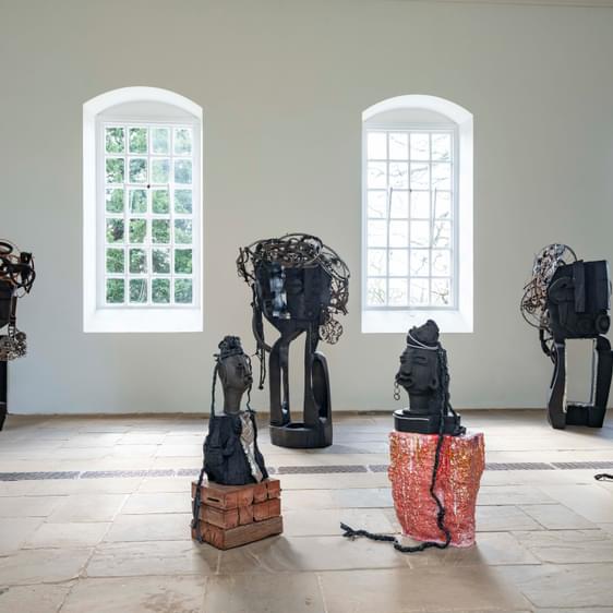 A collection of carved wood and ceramic figures in a gallery.