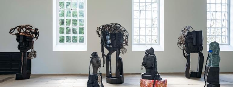 A collection of carved wood and ceramic figures in a gallery.