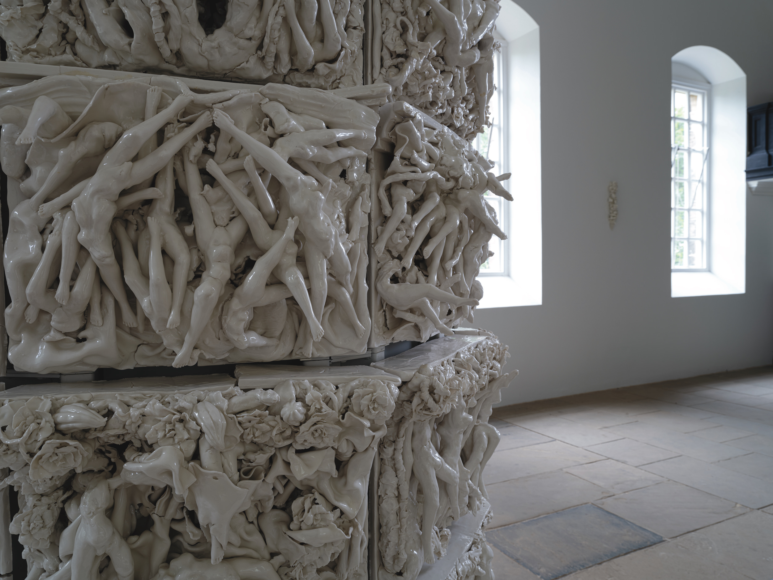 Multiple porcelain tiles of legs and torsos intertwined.