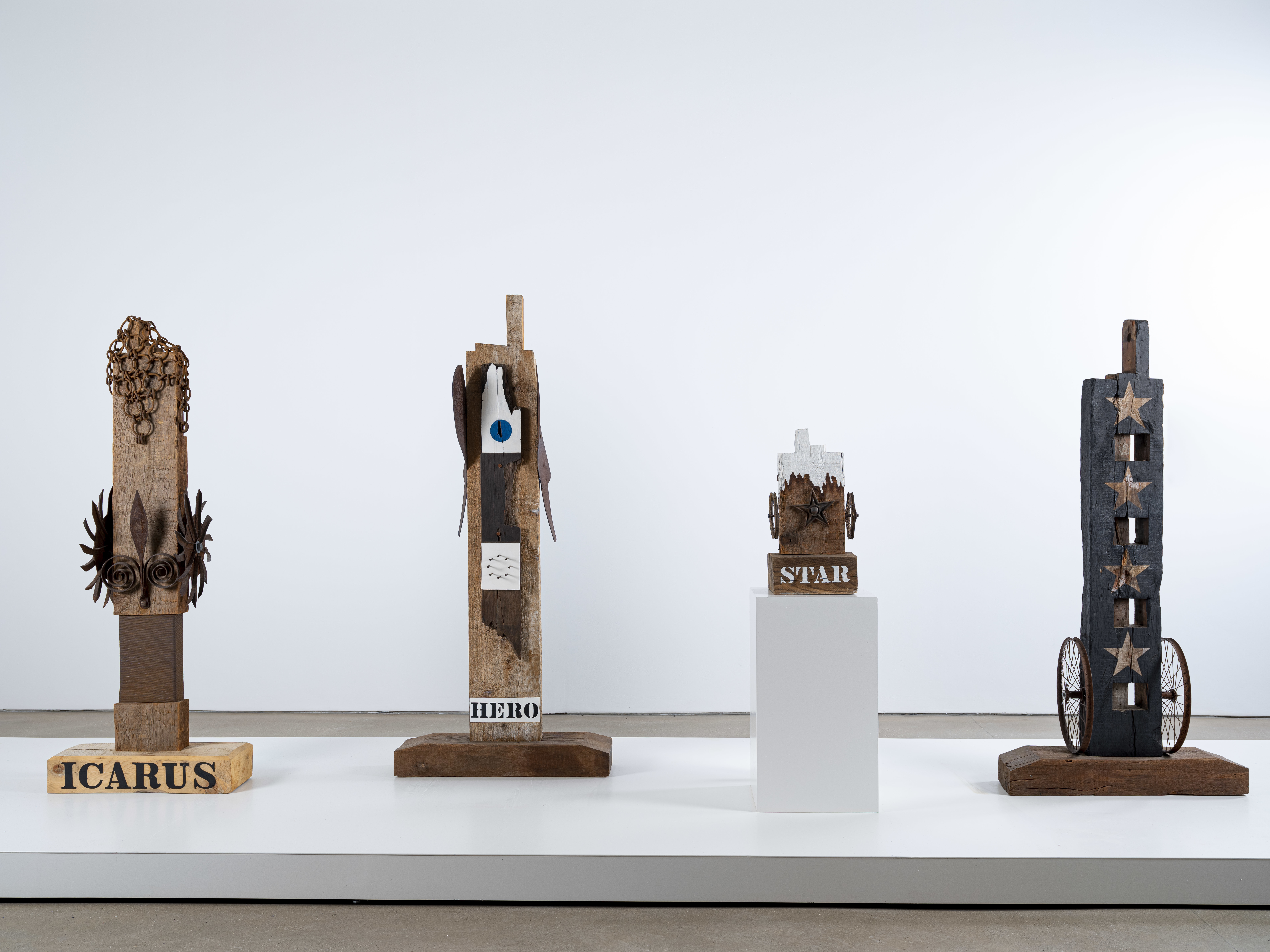 Four sculptures on a plinth in a gallery.