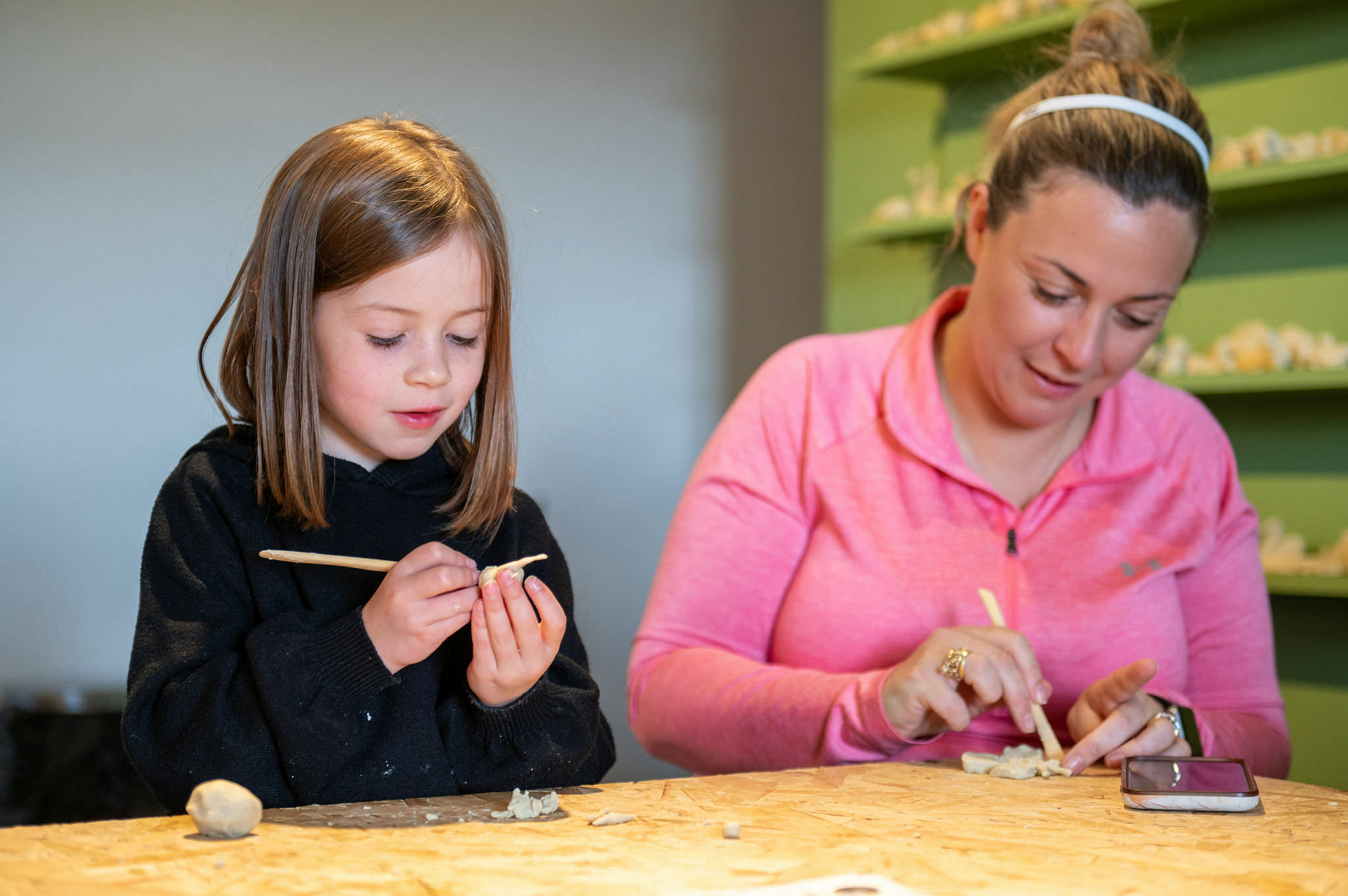 An adult and child making wax animal models