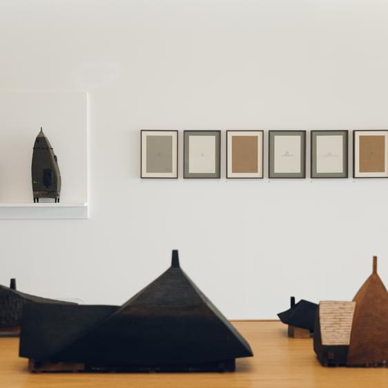 A display of carved wooden houses and drawings.