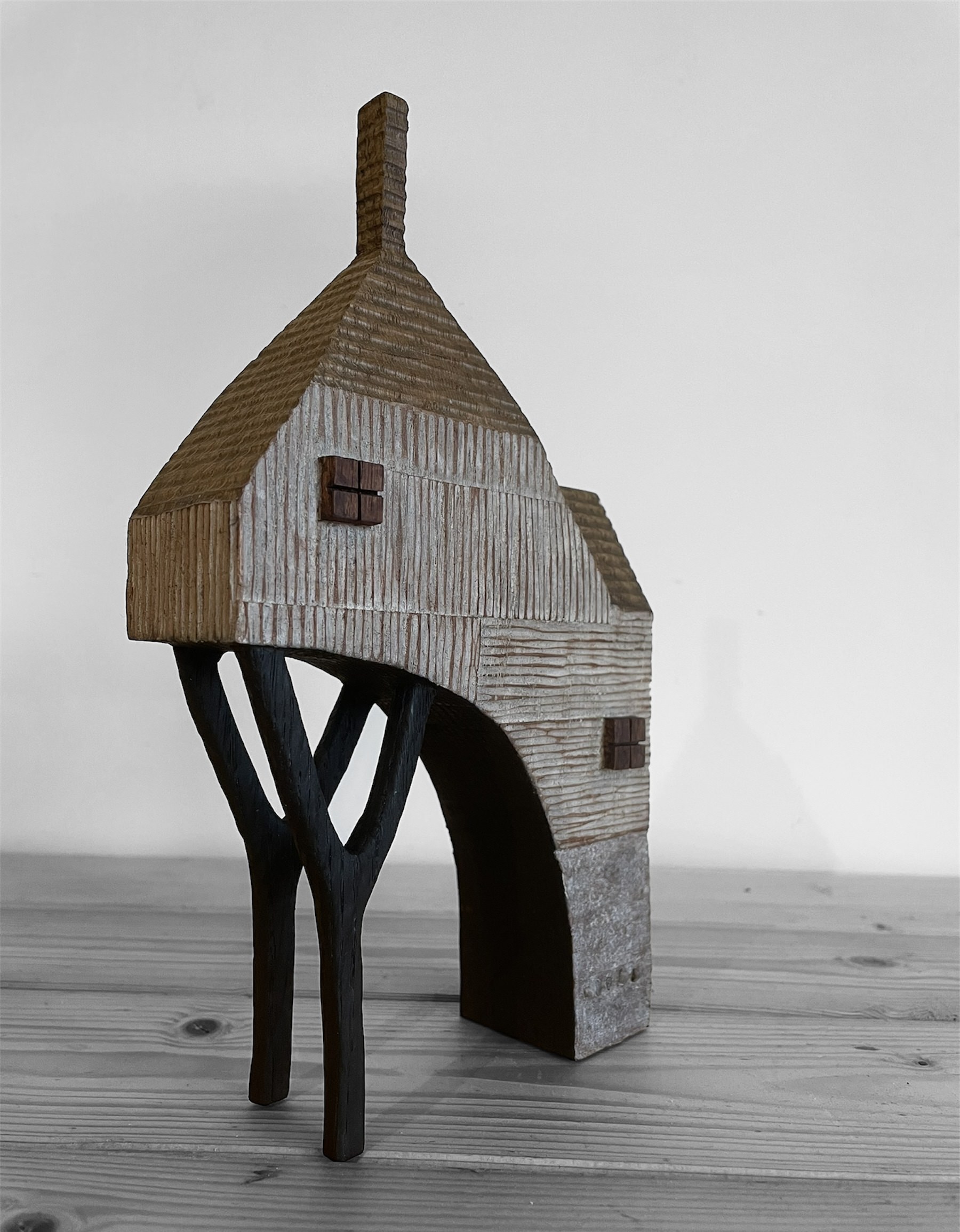 Miniature wooden house with chimney and stilts.