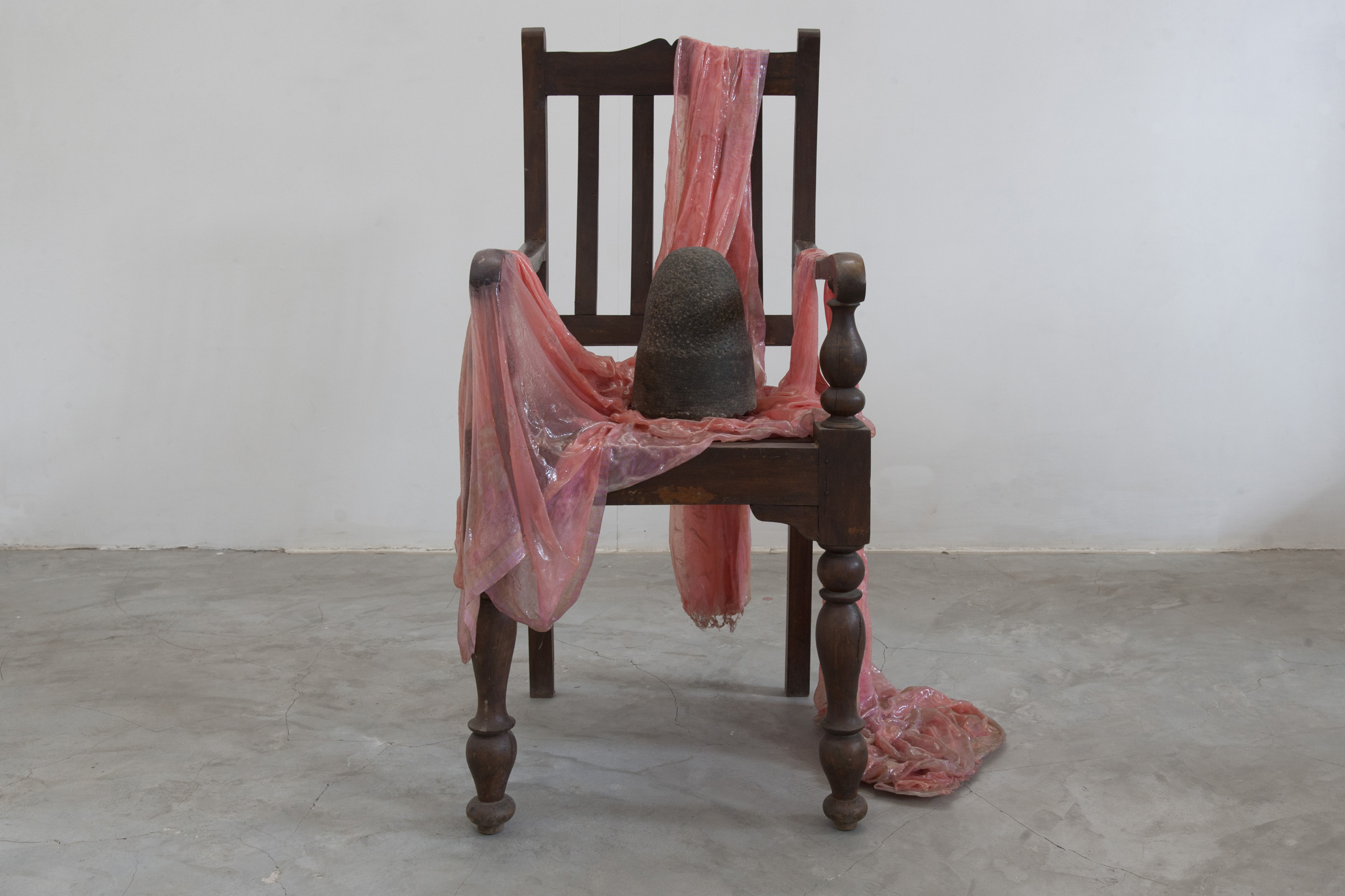 A wooden chair, covered in a sheet of shiny pink plastic