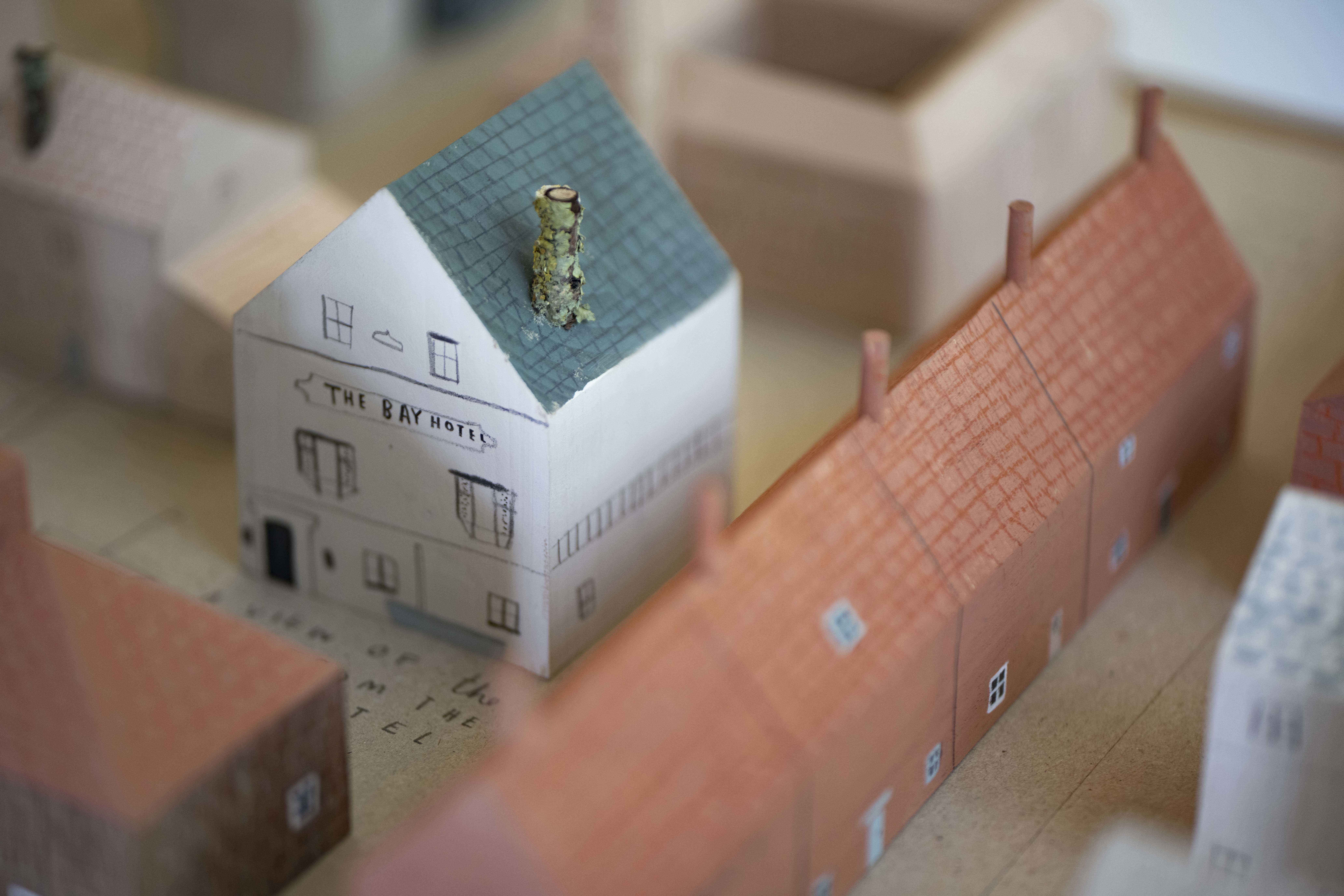 Miniature wooden painted terraced houses and a house.