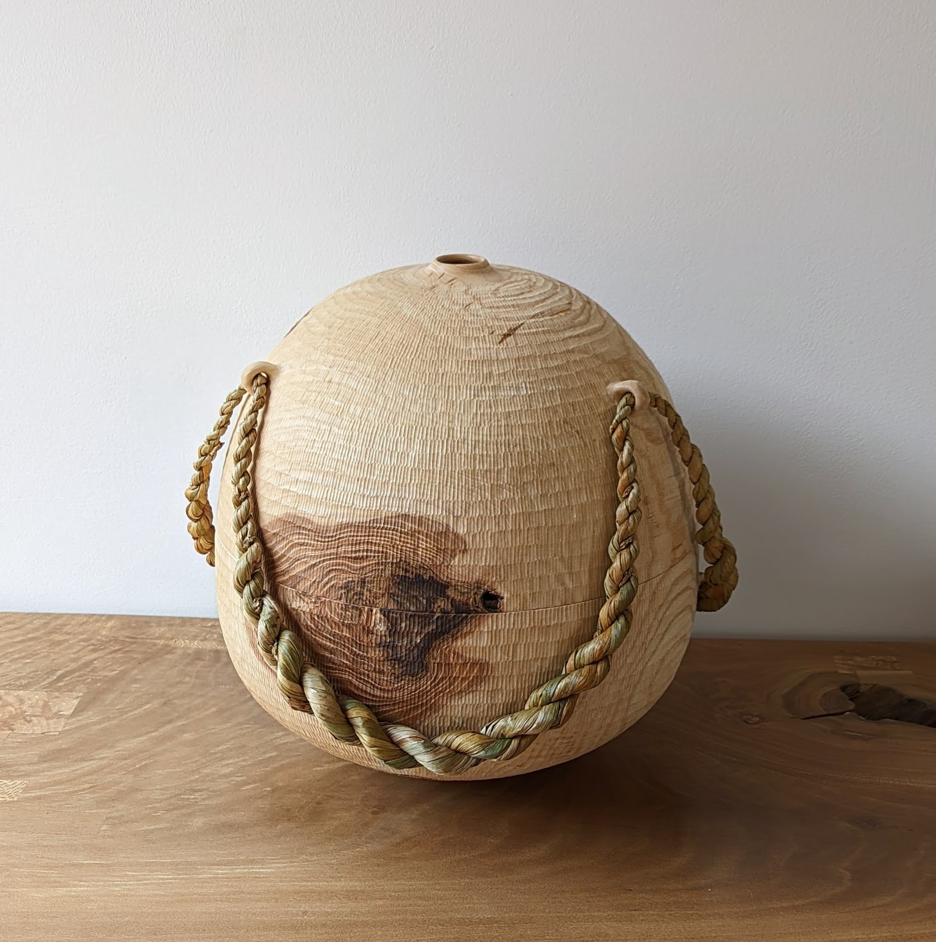 A carved wooden vessel with rope embellishments