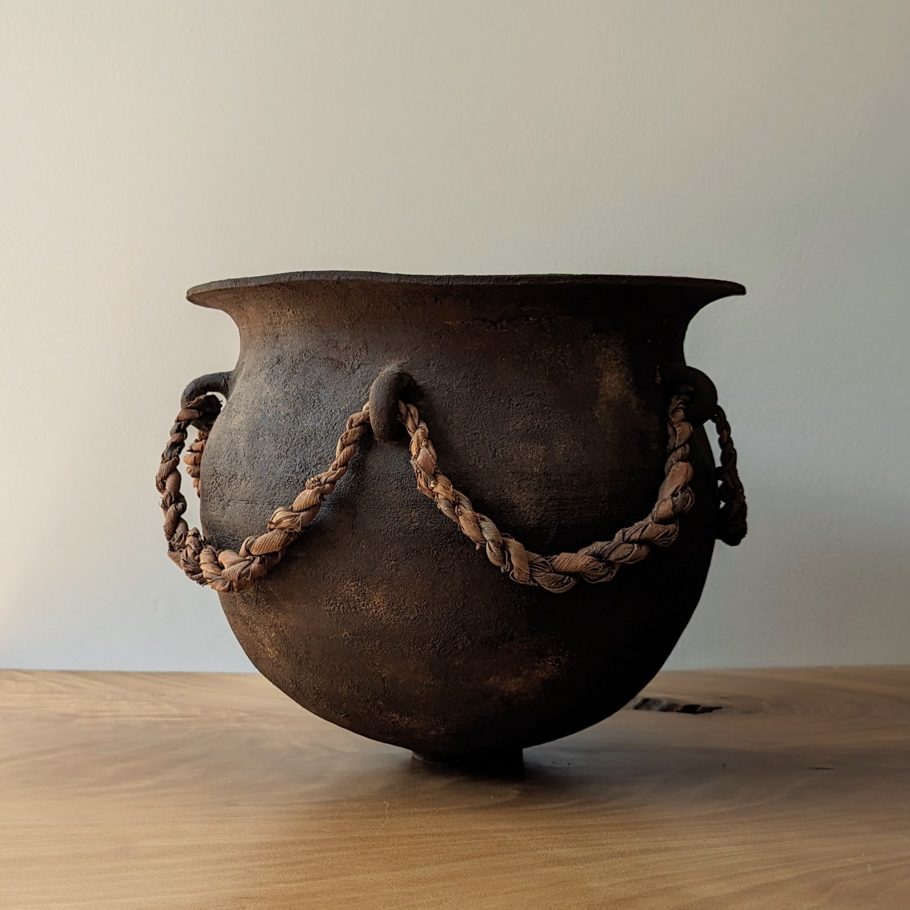 A carved wooden vessel with rope embellishments