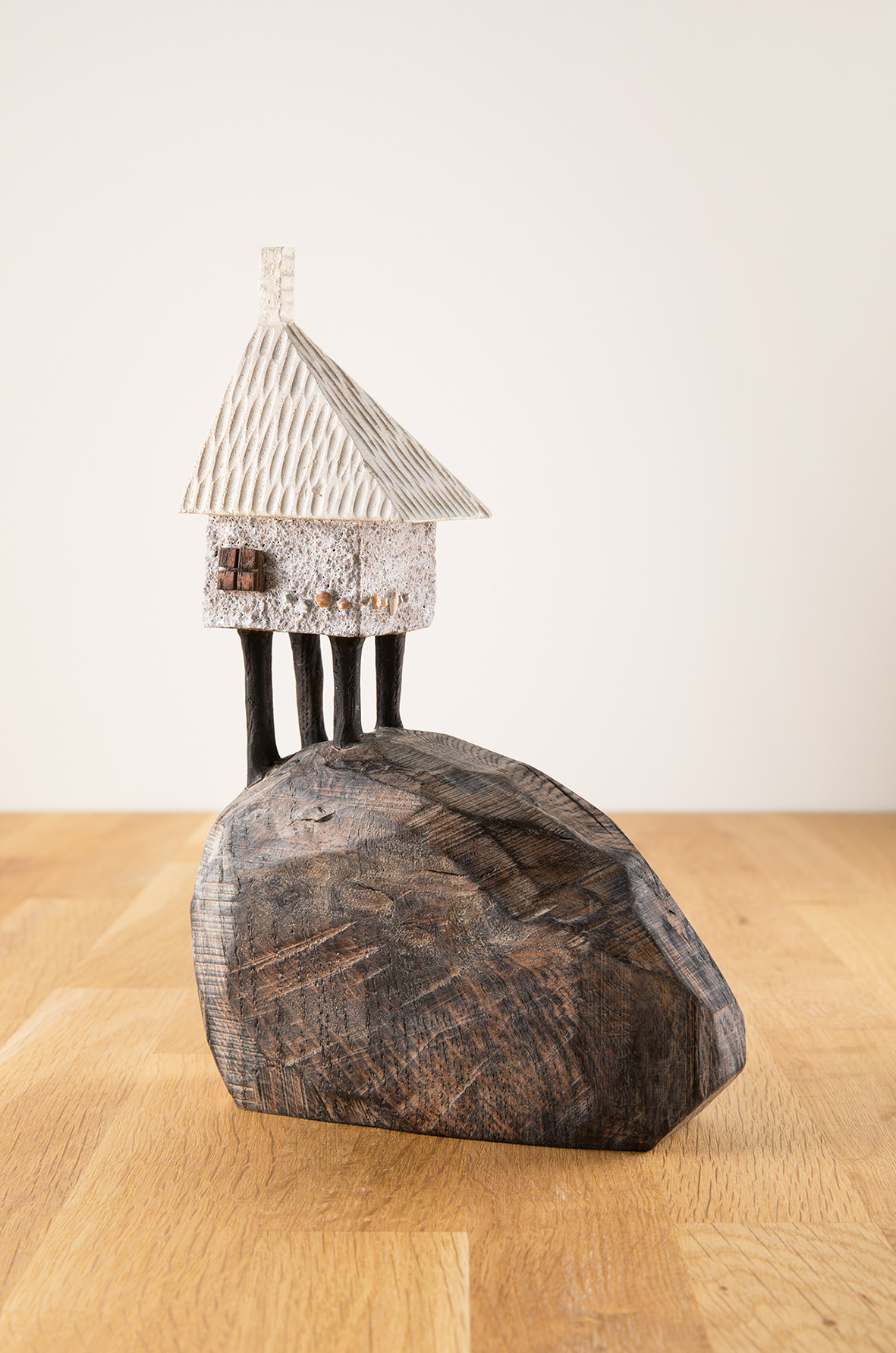 A miniature carved wooden house on top of a carved wooden mound