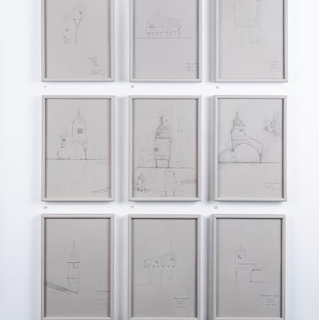 Nine framed pencil drawings of miniature houses.