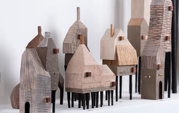 Multiple miniature handcrafted houses on a shelf.