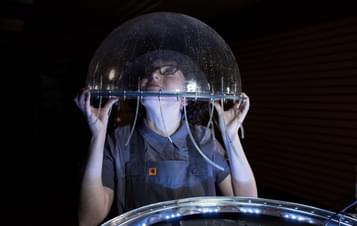 a person with their head inside a clear bubble-like plastic dome