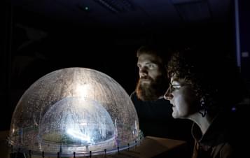 Two people looking into an illuminated plastic dome