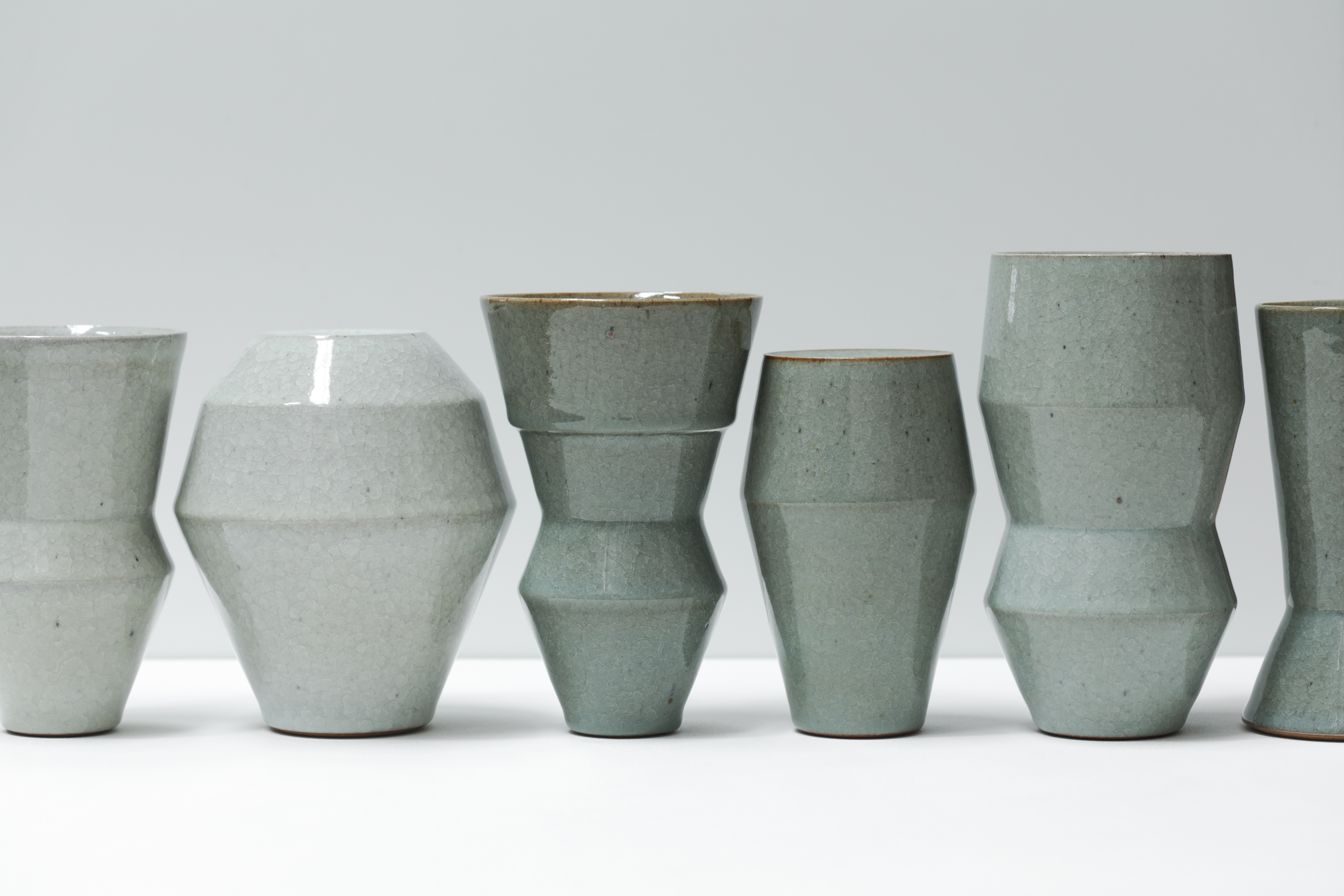 A row of glazed green and grey vases