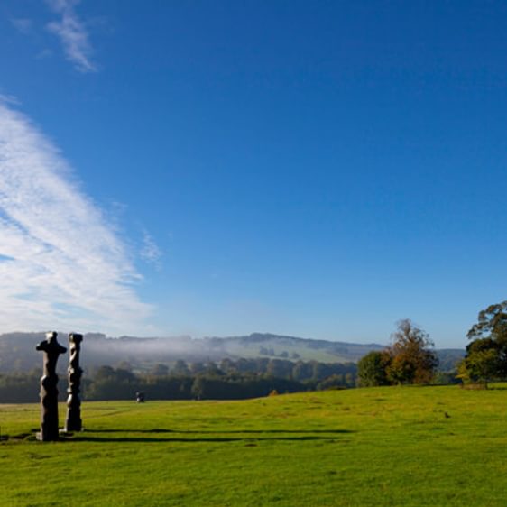Three tall thin bronze sculptures looking out over the landscape