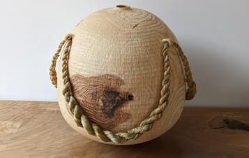 A carved wooden vessel with rope embellishments